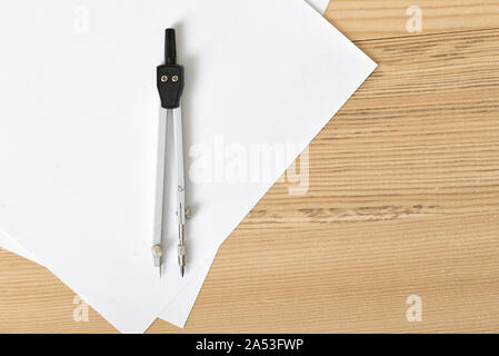 Engineering compass with white paper which is on wooden plank. Stock Photo