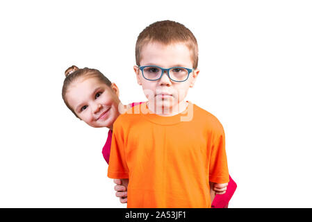 Little girl peeks out from behind a boy. Isolated on a white background. Stock Photo