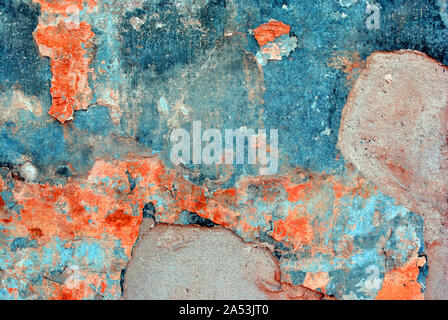 Cracked soft coral red and white paint, plaster surface on gray cement wall, grunge horizontal shabby background detail close up Stock Photo