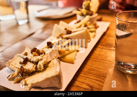Assorted cheese plate with walnuts on a wooden table at Basquery, Bilbao, Basque Country, Spain Stock Photo
