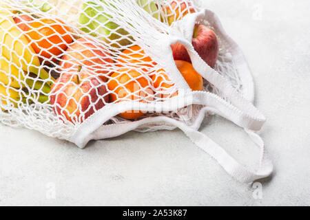 Zero waste eco friendly shopping concept, vegetables fruits in white mesh bag on white kitchen table, selective focus Stock Photo