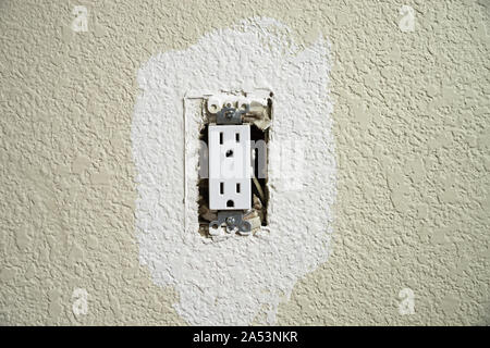 wall electrical outlet with the cover off being painted on a textured wall Stock Photo