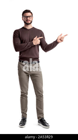 A bearded man in smart casual clothes looks straight and points sideways with both hands on a white background. Stock Photo