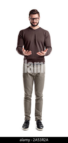 A young bearded man in cargo pants looks down on his both hands cupped as if holding something. Stock Photo