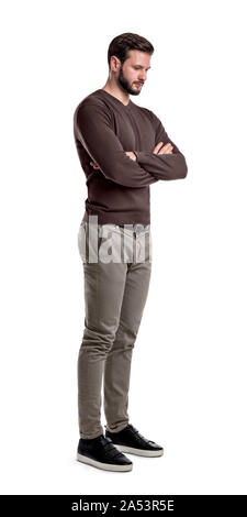 A bearded man in smart casual clothes stands in half-turn with arms folded and looks down. Stock Photo