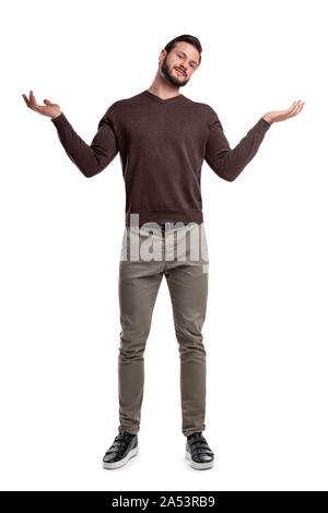 A bearded man in casual clothes stands with both arms up and a questioning face expression. Stock Photo