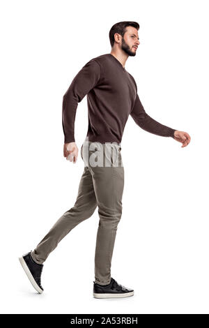 A bearded man in casual garb walks in a side view and looks suspiciously sideways. Stock Photo