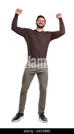 A happy bearded man stands in casual wear smiling and holding arms up in victory in tight fists. Stock Photo