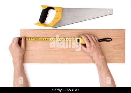 Close up view of a man's hands measuring wooden plank with tape line, isolated on white background Stock Photo