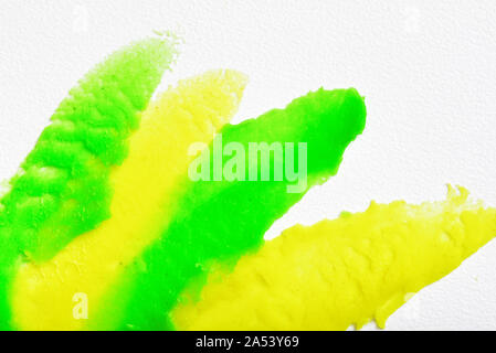 Green and yellow stripes of plasticine spread in a thin layer on the white textured background. Stock Photo