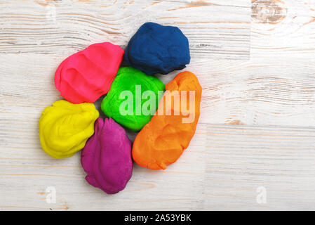 Six colorful lumps of crumpled plasticine put together on a wood surface Stock Photo