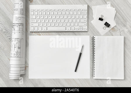 Top view of draftsman's workplace with keyboard, paper, pen, notebook and rolled draft Stock Photo