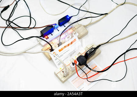 Multiple overloaded power boards extension socket with a MERALCO Disconnection Notice on white isolated background. Stock Photo