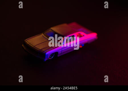 A toy car under red and blue lights, dark background. Stock Photo