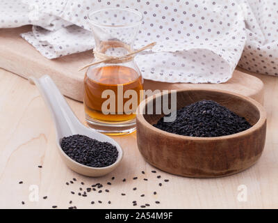 Black sesame oil and sesame seeds set up on wooden table Stock Photo