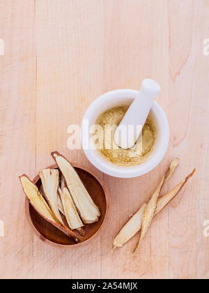 Licorice herbal medicine including powder, chopped and sliced root and mortar on wooden table Stock Photo