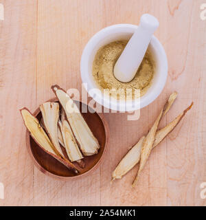 Licorice herbal medicine including powder, chopped and sliced root and mortar on wooden table Stock Photo