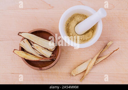 Licorice herbal medicine including powder, chopped and sliced root and mortar on wooden table Stock Photo