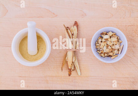 Licorice herbal medicine including powder, chopped and sliced root and mortar on wooden table Stock Photo