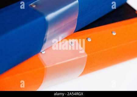 an orange and a blue binder lying in a pile in the office Stock Photo