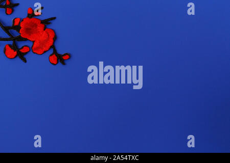 Needlework concept. The photo has an application in the form of red flowers. Plenty of room for text. Blue background. Stock Photo