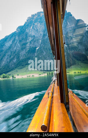 The windows of a tourist boat reflects water and mountains from the Koenigssee (Königssee) in Bavaria, Germany Stock Photo