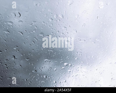 Rain water drop on glass window with dark clouds background - Rainy season atmosphere concept Stock Photo