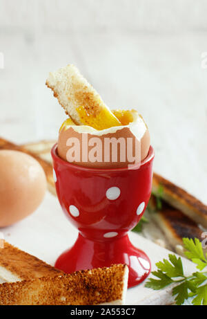 Soft-boiled egg with toasts on a white wooden table Stock Photo