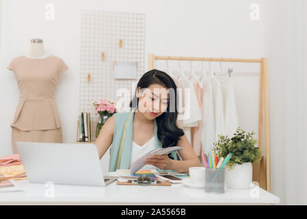 Young Asian fashion designer choosing color for her new collection