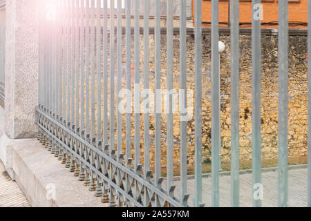 Gray metal fence with concrete columns on a stone wall background of an old building Stock Photo
