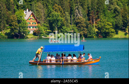 Traditional Wooden pletna boat with tourists  on Lake Bled  in Upper Carniola, Slovenia Stock Photo