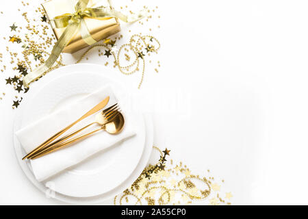 Christmas elegant table setting with dishware, golden decorations and silverware on white background. Top view. Xmas dinner. Stock Photo