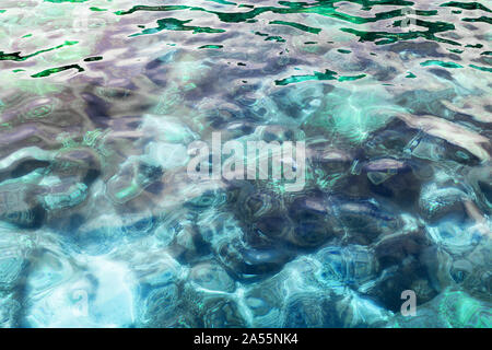 Blue crystal clear sea water, stones texture background, turquoise transparent ocean, underwater coral reef surface close up, sun light reflection Stock Photo