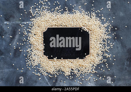 Raw White Sorghum grain with a small chalkboard top view on a gray backgound Stock Photo