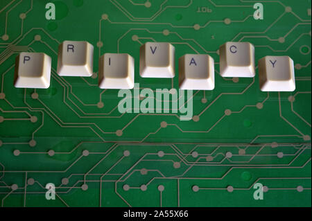 Keyboard keys form the word PRIVACY on green electric circuit in the background. Stock Photo