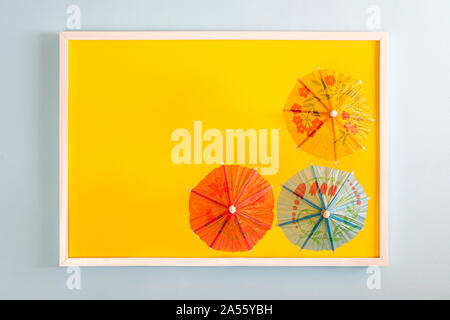 three small japanese paper umbrellas in a white frame on a colored surface Stock Photo