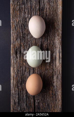 Overhead view of three eggs on a rustic wooden board Stock Photo