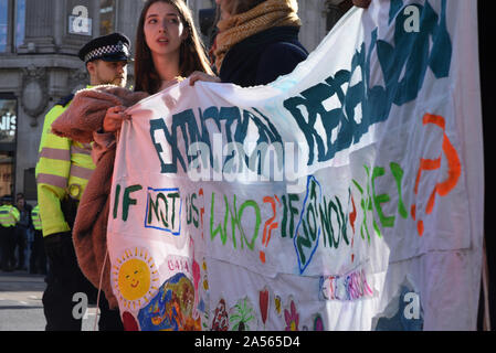 London, UK. 18th Oct, 2019. Young protestors hold an Extinction Rebellion sign as climate change activits occupy London’s Oxford Circus. Credit: Kevin Shalvey/Alamy Live News