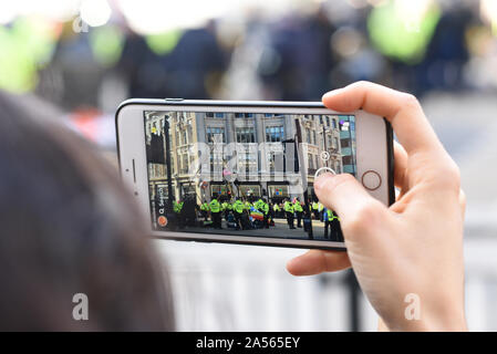 London, UK. 18th Oct, 2019. An onlooker films the scene as climate change activits occupy London’s Oxford Circus. Credit: Kevin Shalvey/Alamy Live News Stock Photo