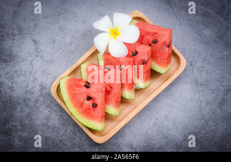 Fresh watermelon slice and white flower on black background / watermelon tropical fruit on wood tray , selective focus Stock Photo