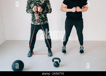 Fitness instructor teaching man using resistance band in studio Stock Photo