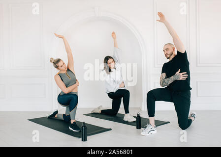Fitness instructor teaching women stretching arm in studio Stock Photo