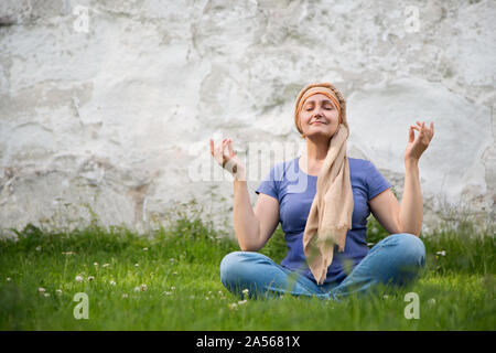 Yoga woman. Portrait of relaxed middle aged woman sitting in yoga pose outdoors in summer day. Stock Photo