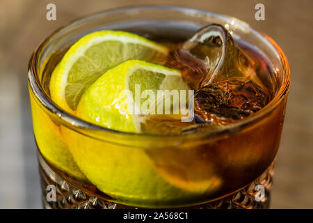 Alcoholic cocktail - Long Island Iced Tea. Iced tea with lemon in glass, close-up. A brown sweet drink. Stock Photo