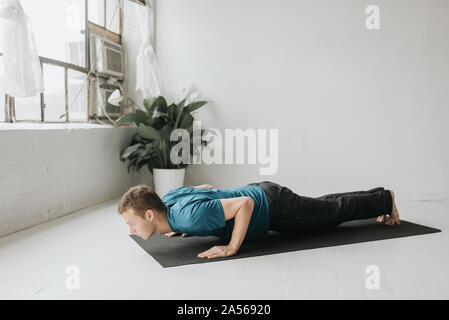 Man doing half plank in yoga studio Stock Photo