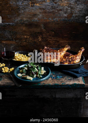 Rustic still life with chipotle chicken, corn and rainbow chard on wooden table Stock Photo