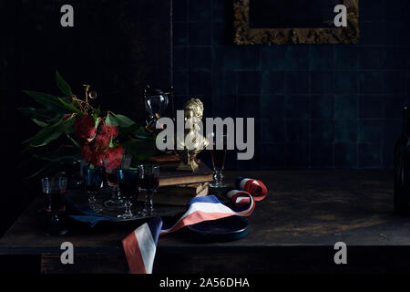 A Bastille Day celebration, tray of glasses with red wine, traditional old master painting and a red white and blue ribbon, colours of the French flag. . Stock Photo