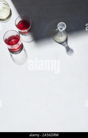 High key still life with glasses of red wine and white white wine on white table, overhead view Stock Photo