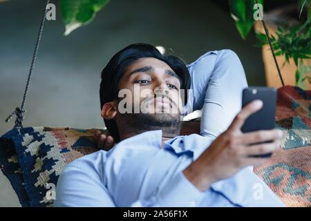 Businessman using cellular phone on swing Stock Photo