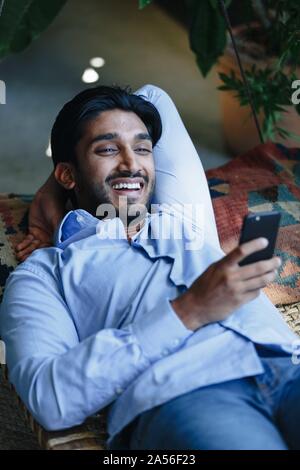 Businessman using cellular phone on swing Stock Photo